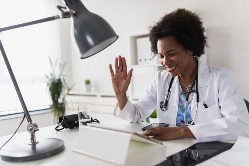 African American health care provider sitting in her office engaging in a telehealth services.