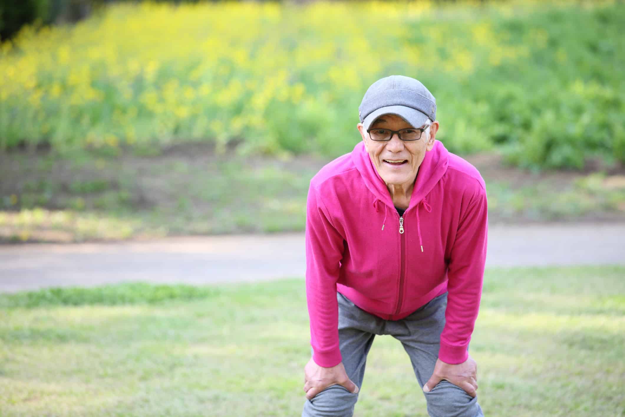 tired senior Japanese man after workout outdoors portrait of tired senior Japanese man in pink wear resting after workout at the park