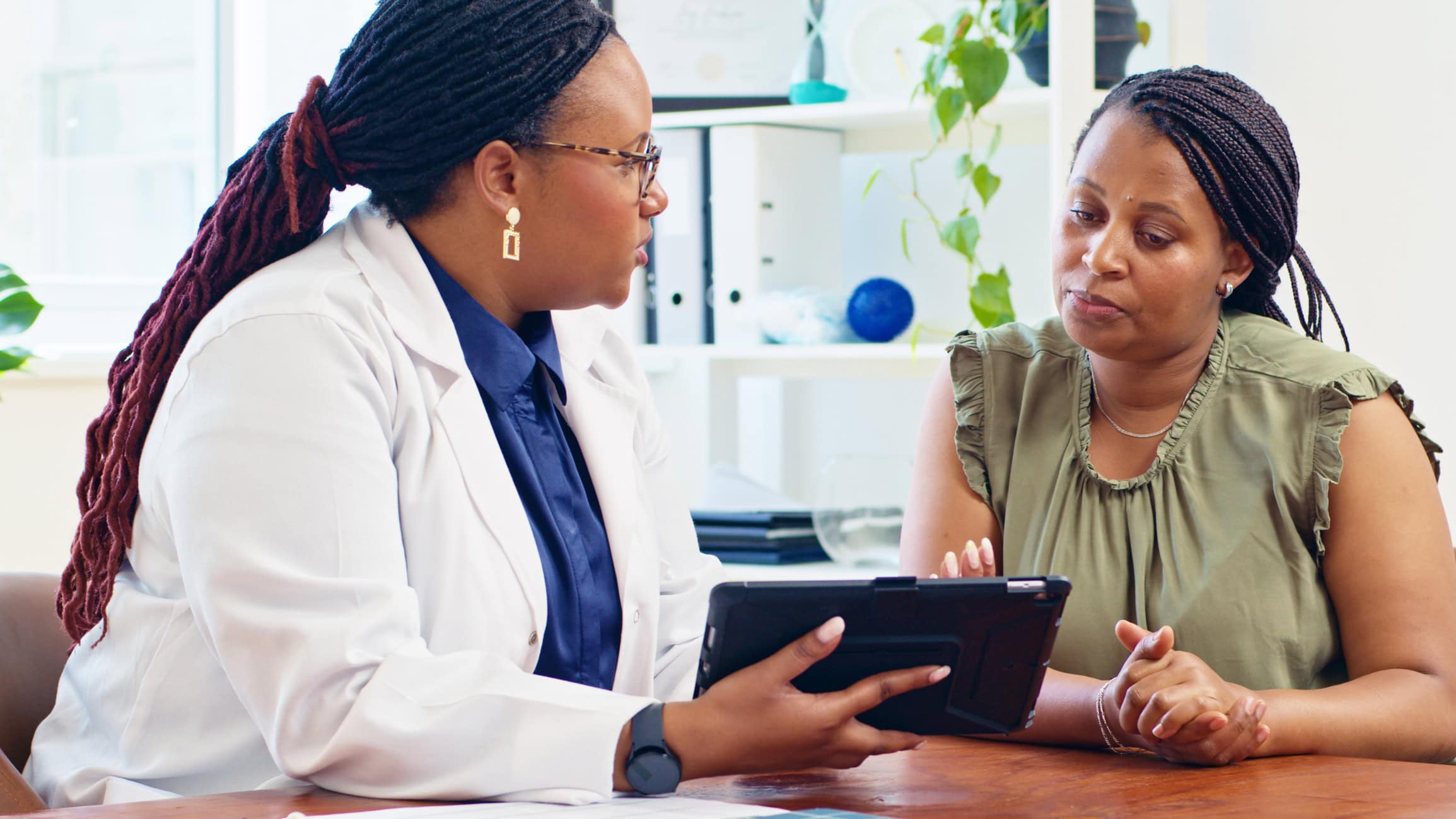 A doctor consults with a patient using a digital tablet in a medical office, discussing healthcare and treatment options. Professional healthcare setting showcasing patient care and technology.
